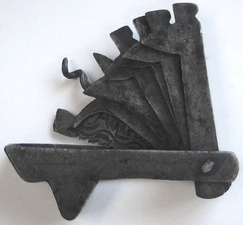 Iron folding fleam with 4 fleam blades one bandage blade, a straight blade, corkscrew, and saw.  Mexican in origin probably 1790-1820.
